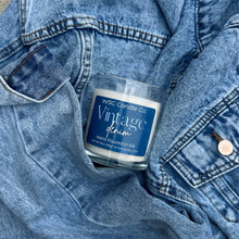Load image into Gallery viewer, Candle labeled 'Vintage Denim' by WSC Candle Co inside a denim jacket.