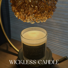 Load image into Gallery viewer, Wickless candle on a stand with a decorative lamp in the background