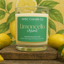 Load image into Gallery viewer, WSC Candle Co. Limoncello crème candle with lemons and green leaves in the background
